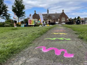 A path through a park with colourful wavy lines chalked on the path.